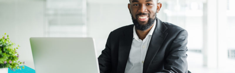 portrait of handsome African black young business man working on laptop computer at office desk